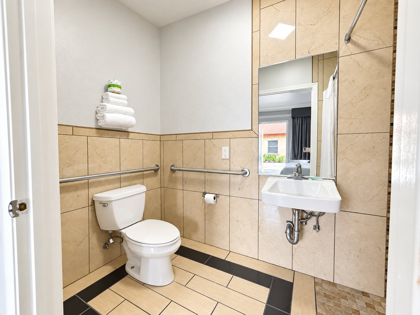 Accessible bathroom with a wall-mounted roll-under sink, grab bars and mirror