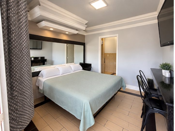 Motel room with a green bedspread, desk and two chairs