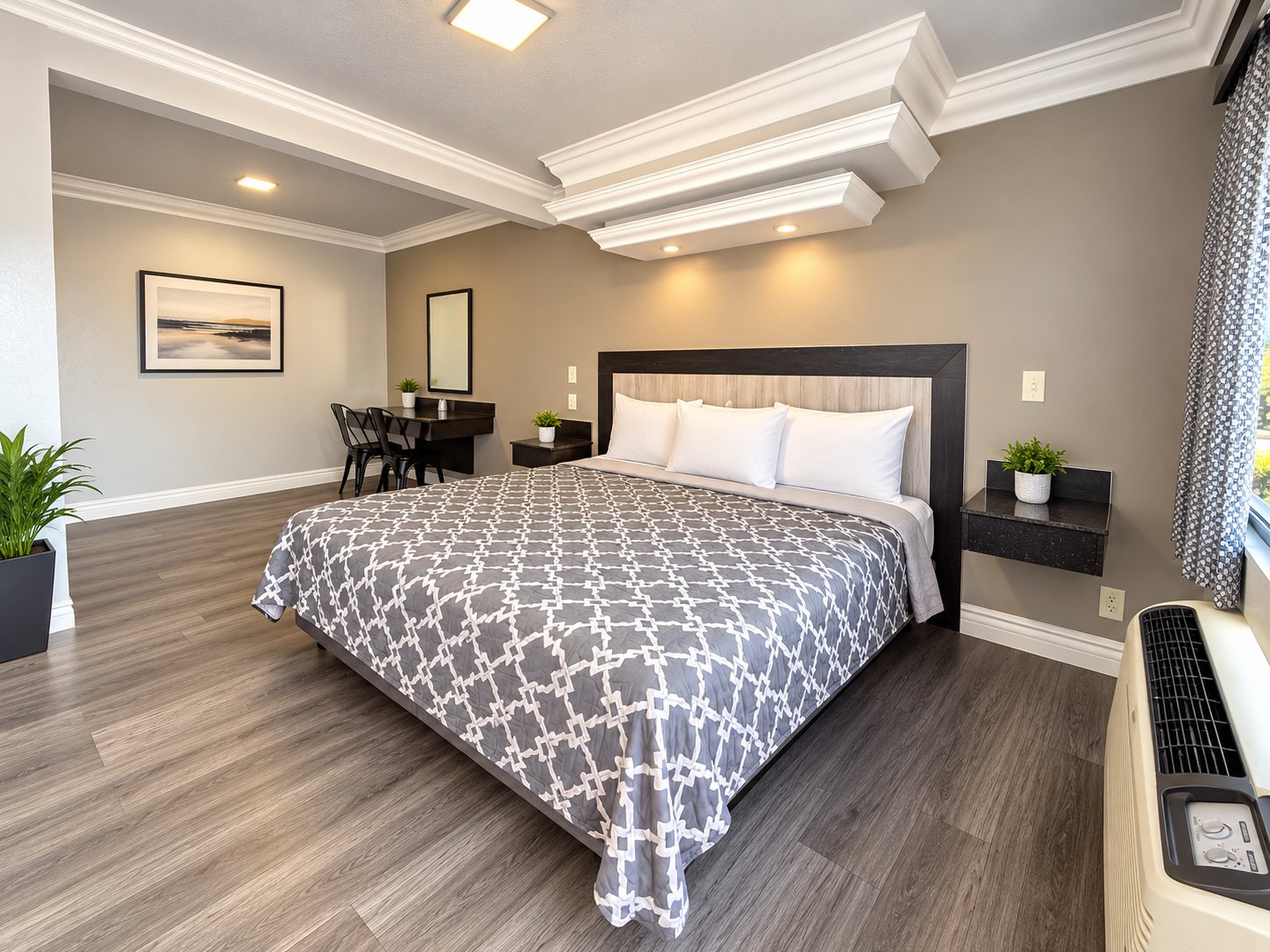 King room with a dark wood headboard, wide bed and wood-look flooring