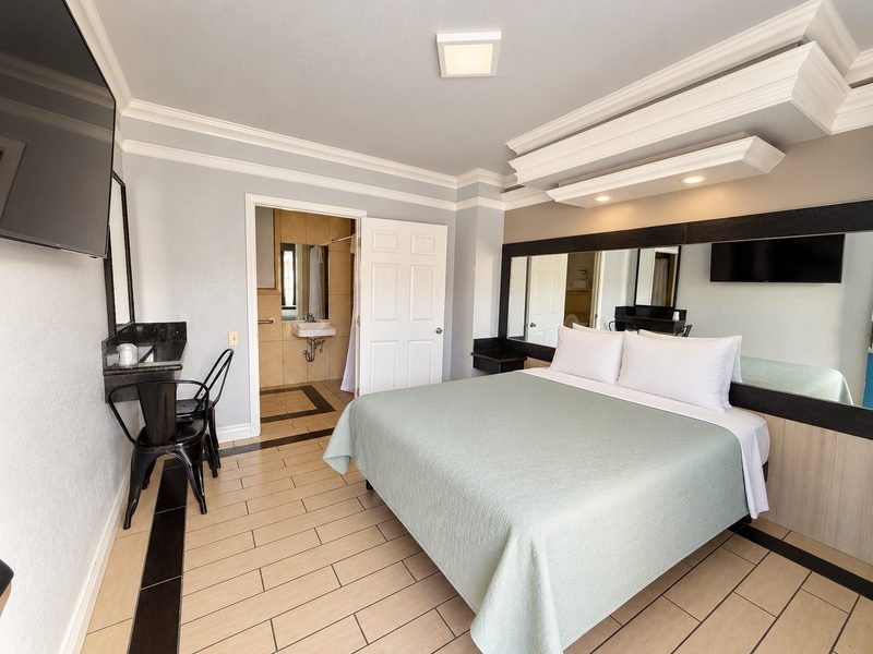 The accessible room, with the bed, tiled floor and the widened bathroom doorway.
