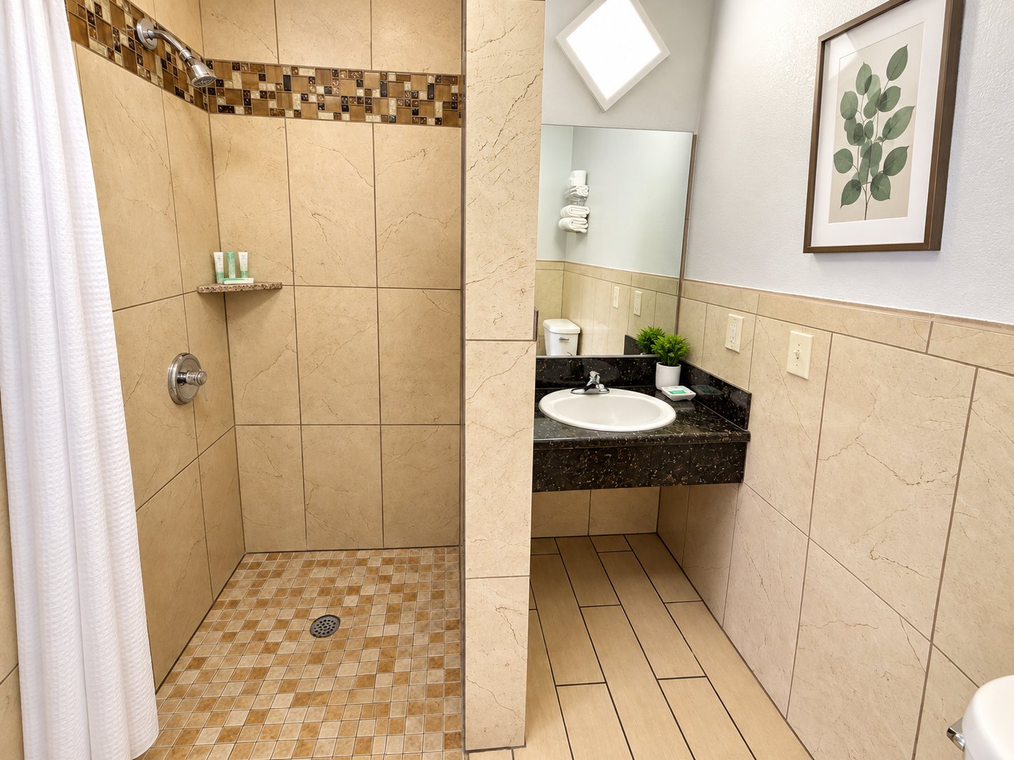 Tiled bathroom with a large walk-in shower and dark granite vanity